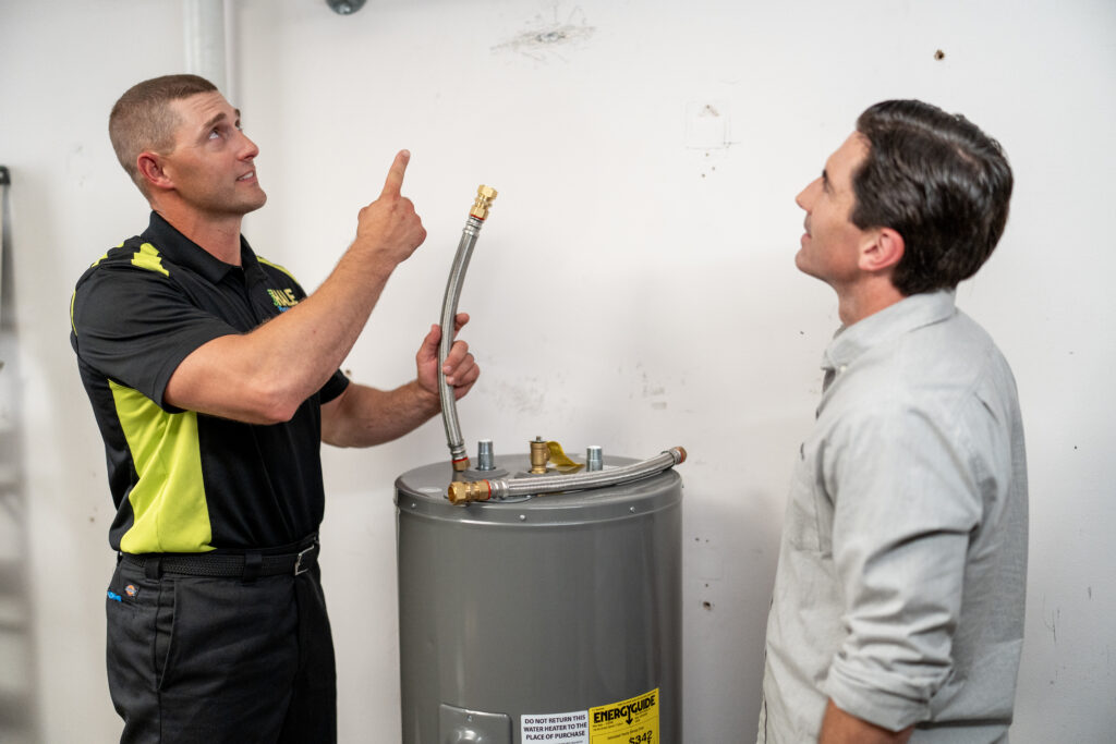 plumber installing a new hot water heater with client
