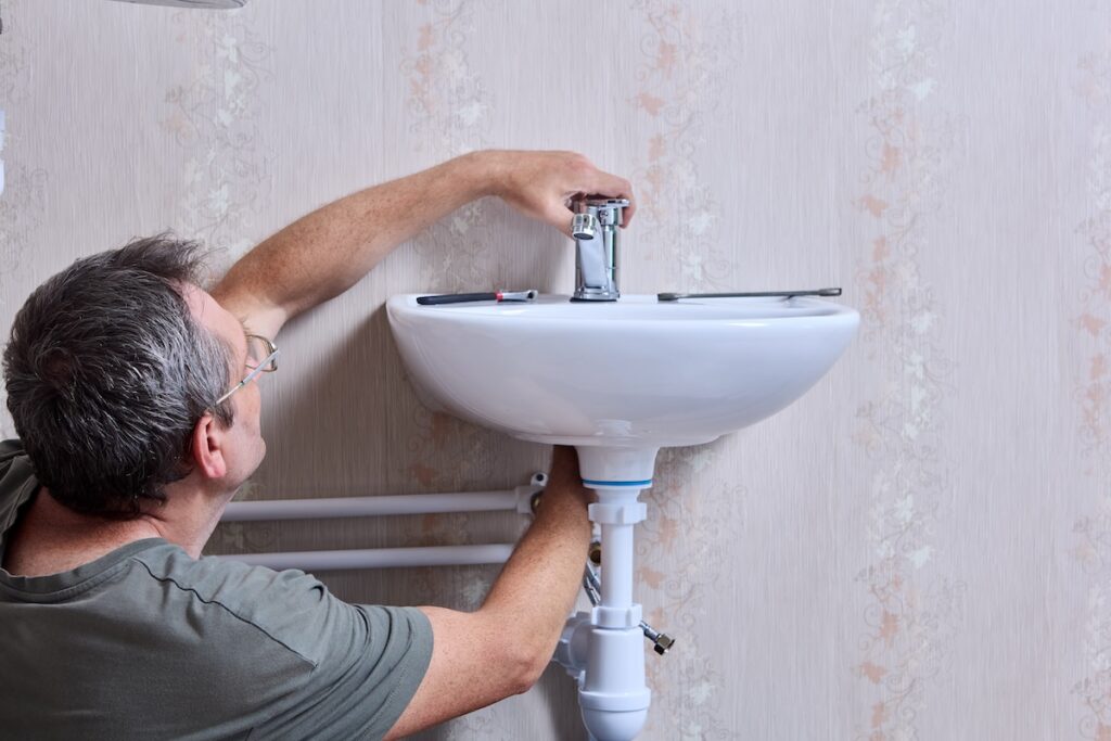 plumbing working on sink faucet