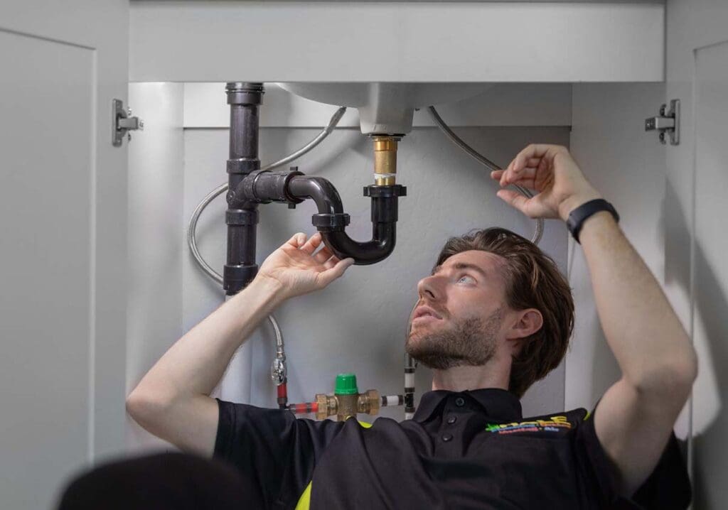 plumber working on under-the-counter plumbing