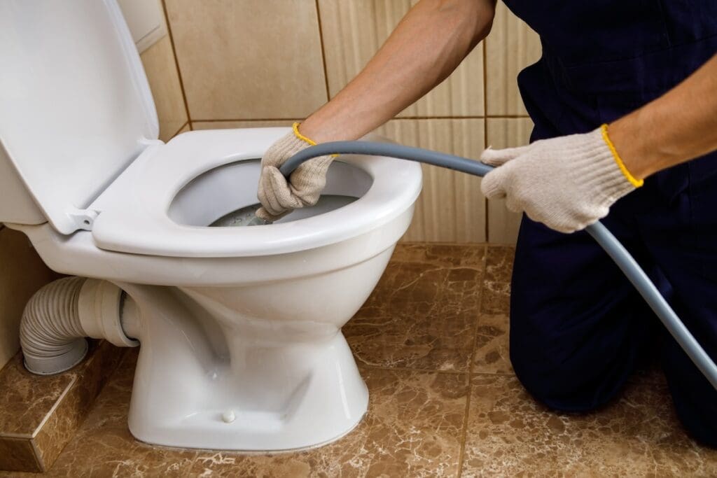 plumber unclogging toilet