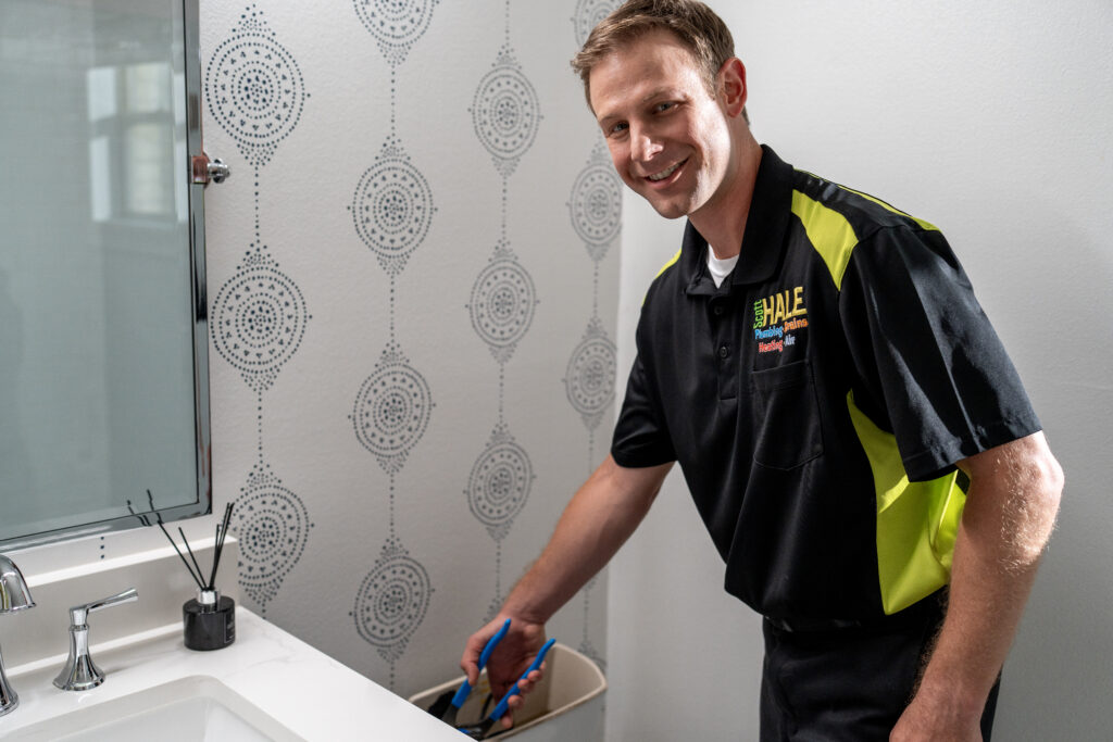 smiling plumber working on back of toilet